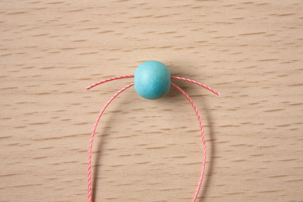 2.Take another 8mm bead, hold it so the hole is horizontal and take one thread through left to right, and the other right to left. This is called a crossover bead.