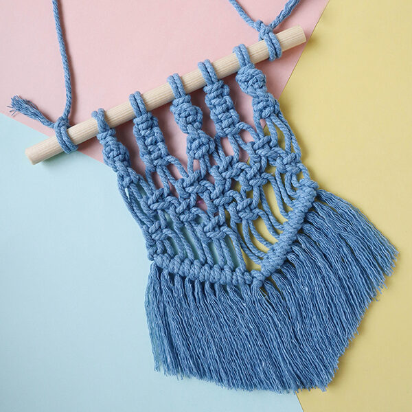macrame wall hanging in light blue on a pastel background