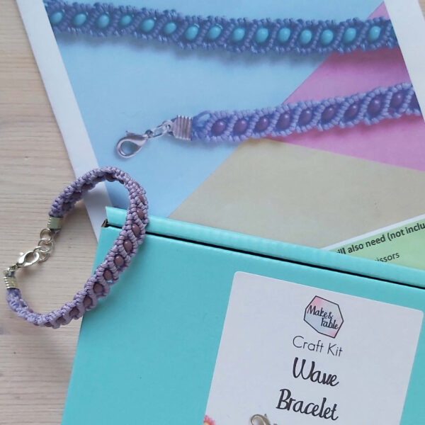 beaded macrame bracelet kit image, showing the finished bracelet in lilac and purple , with the aqua blue box and instruction booklet