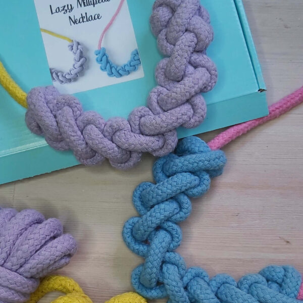 macrame rope necklace kit, showing a finished yellow necklace with lilac knotting, a pink necklace with blue knotting on an aqua blue box