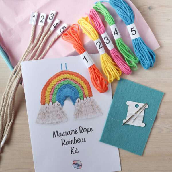 Macrame rope rainbow kit image, showing the open kit box with the instruction booklet and materials from the kit laid out. The rope and yarn are all neatly numbered.