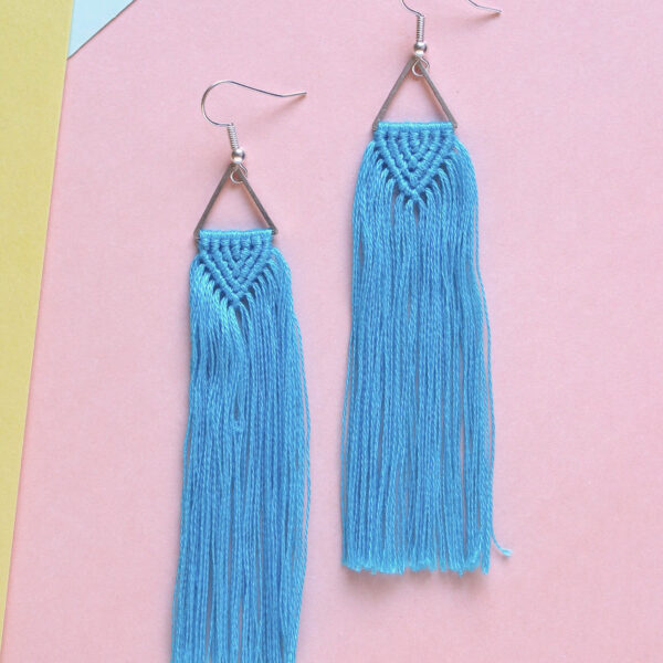 Macrame tassel earrings kit image show a finished pair of knotted earrings, with a triangle connector and long fringe in turquoise blue