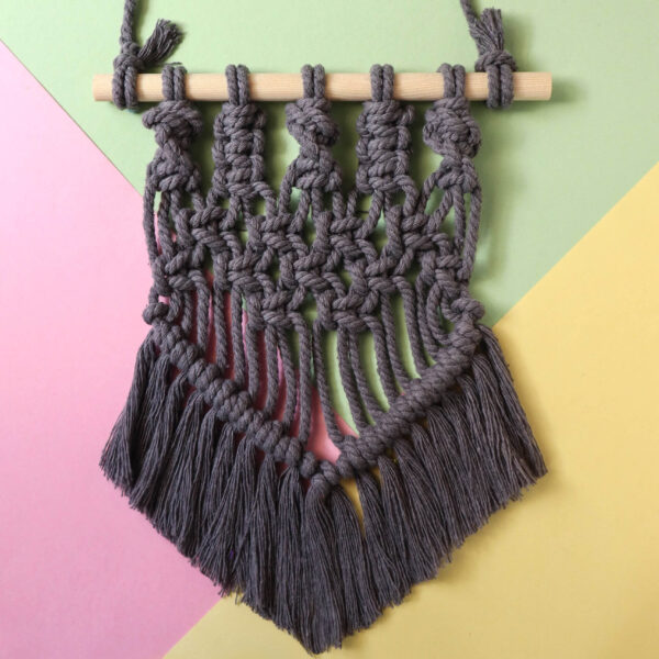 macrame wall hanging in grey on a pastel background