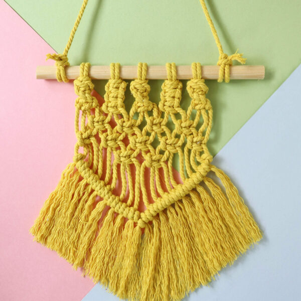 macrame wall hanging in yellow on a pastel background