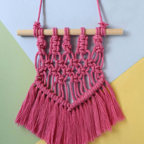 macrame wall hanging in rose pink on a pastel background