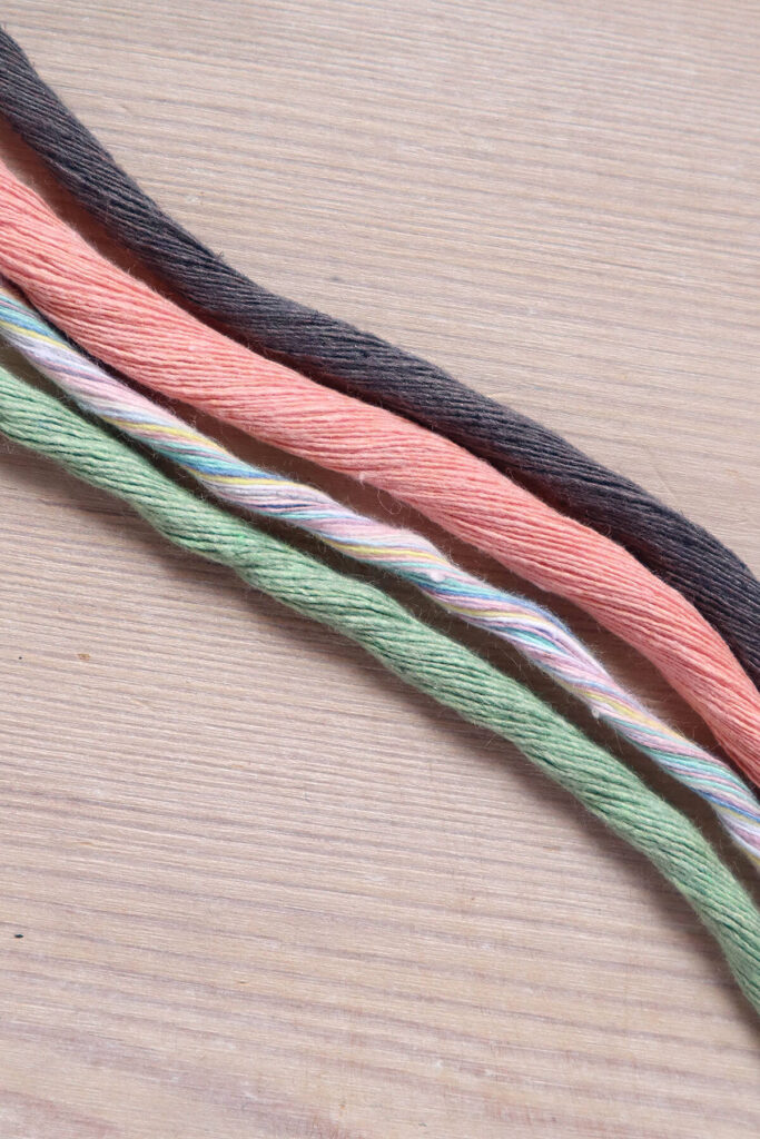 Four thicknesses of single twist macrame string on a wooden background