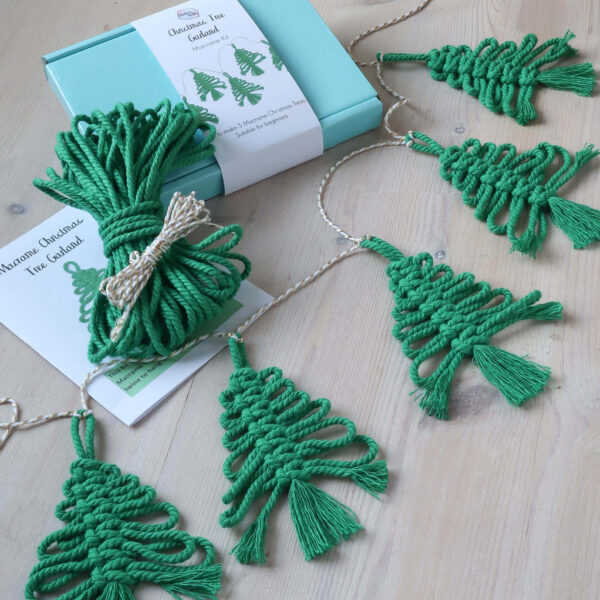 Macrame Christmas Tree Garland Kit image, with a completed garland of 5 macrame trees, and a bundle of green cord.