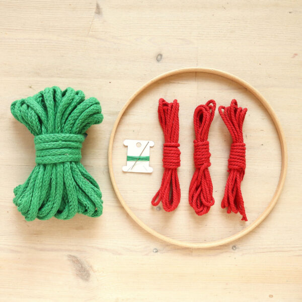 macrame Christmas wreath kit contents: wooden hoop, green and red cord and needle and thread