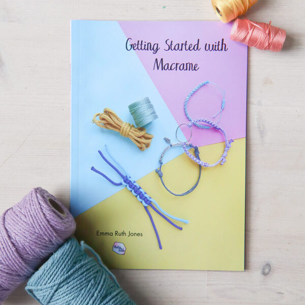 Printed getting started with macrmae book on a wooden background with reels of cord and thread