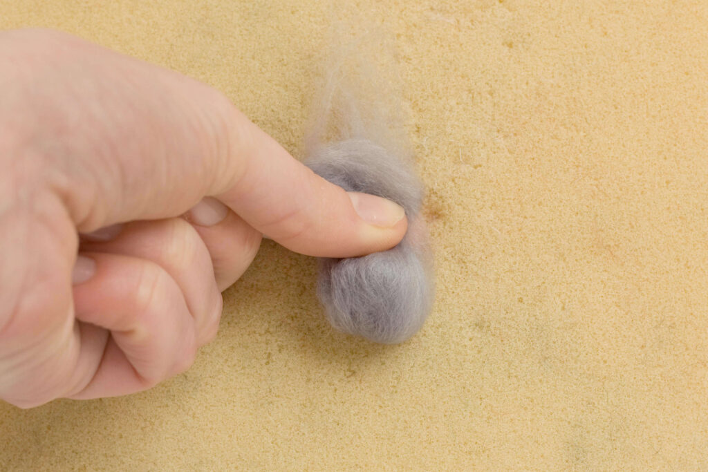 Needle Felt Bunny Rabbit Tutorial A smaller ball of grey roving rolled up, with some of the ends left loose.