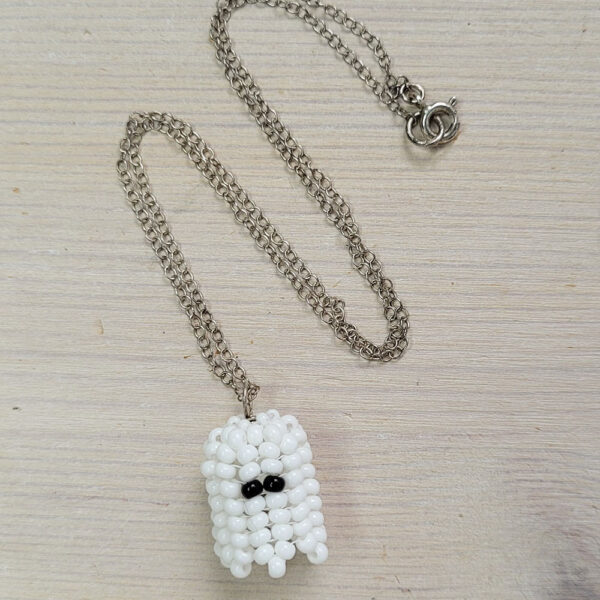 Beaded ghost necklace on a wooden background