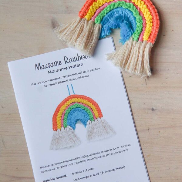 the a5 macrame rainbow pattern booklet with a finished rainbow on a wooden table