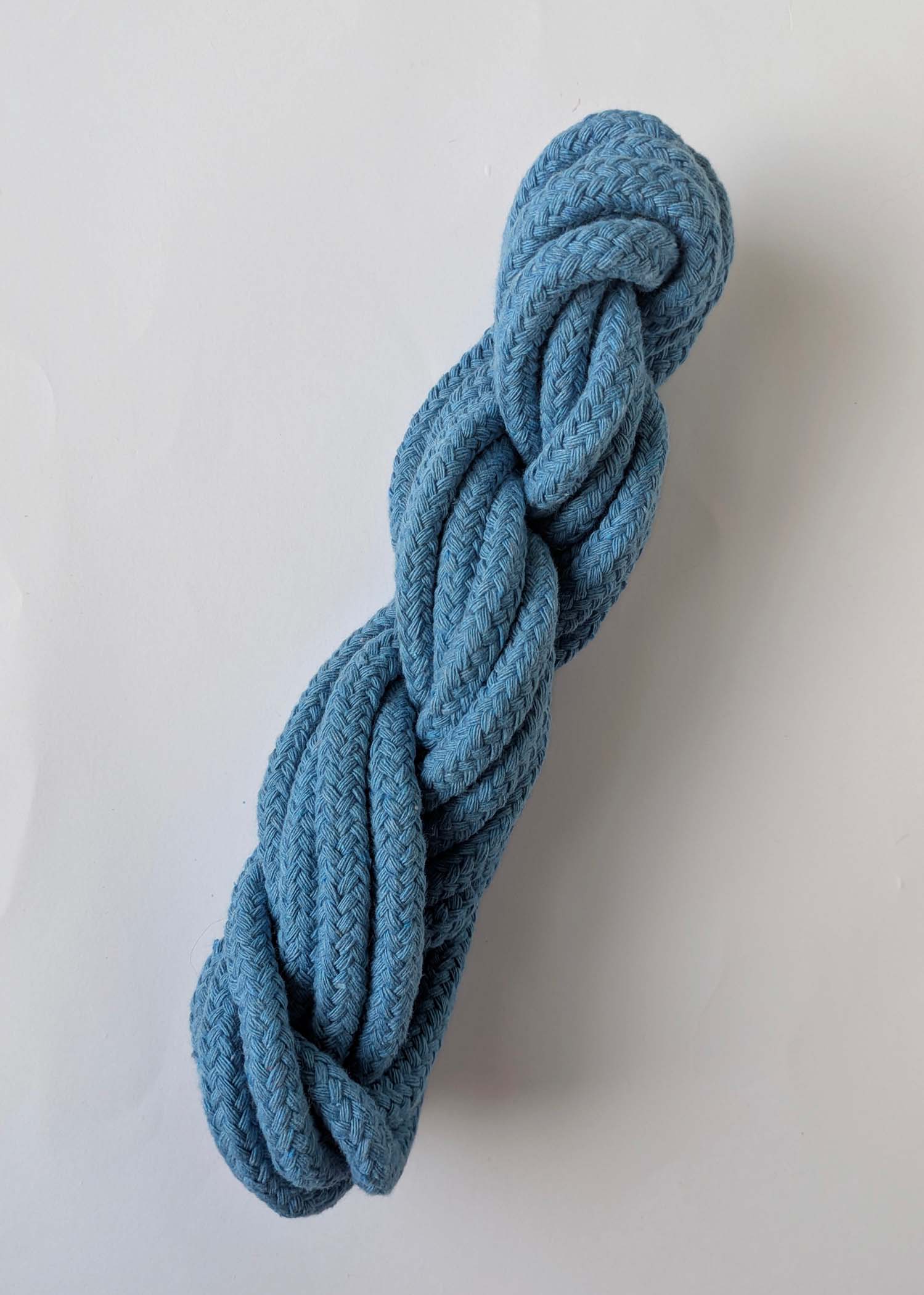 A skein of blue 10mm macrame cord on a white background