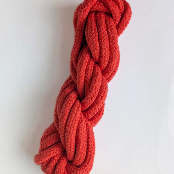 A skein of coral 10mm macrame cord on a white background