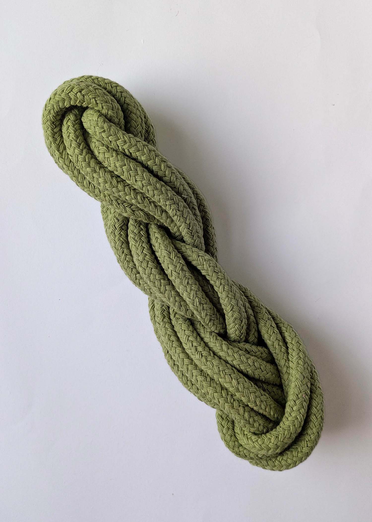 A skein of sage green 10mm macrame cord on a white background