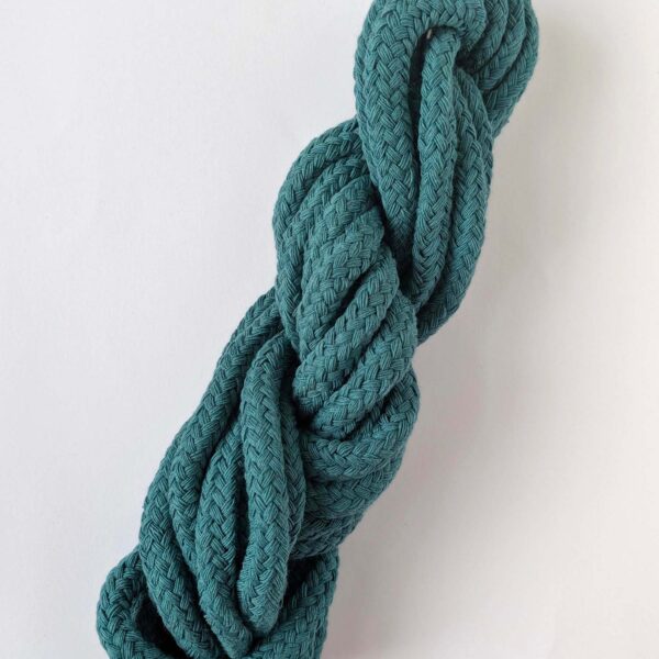 A skein of teal 10mm macrame cord on a white background