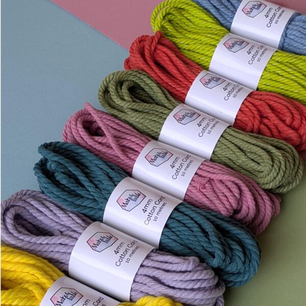 Bundles of 4mm macrame cord in a row, on a pastel background