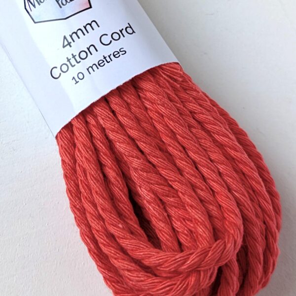 Close up of a bundle of 4mm macrame cord in a bright coral