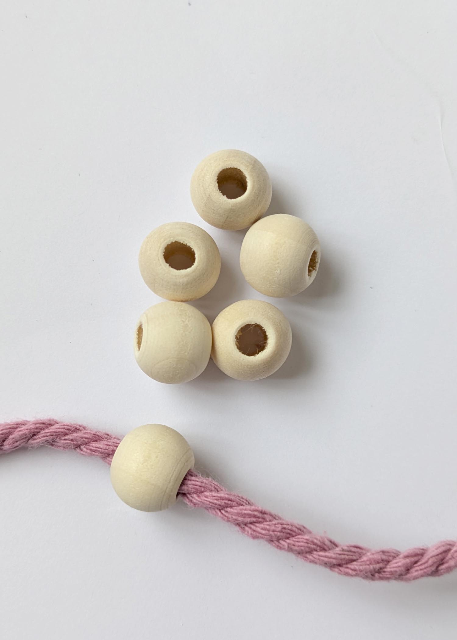 12mm wooden beads, with a natural finish and a large hole, with one threaded into macrame cord