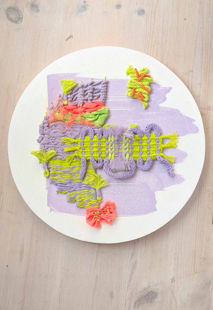 Mixed Media Textiles - a textile art piece on a circular canvas, including weaving, embroidery and macrame in bright neon colours
