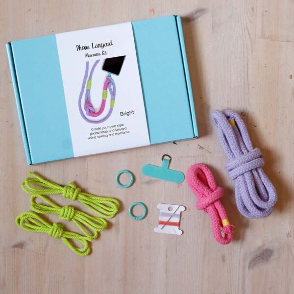 Macrame lanyard kit box and contents in bright. A rope lanyard in lilac, rose pink and neon green with a turquoise fixings and phone tether tab