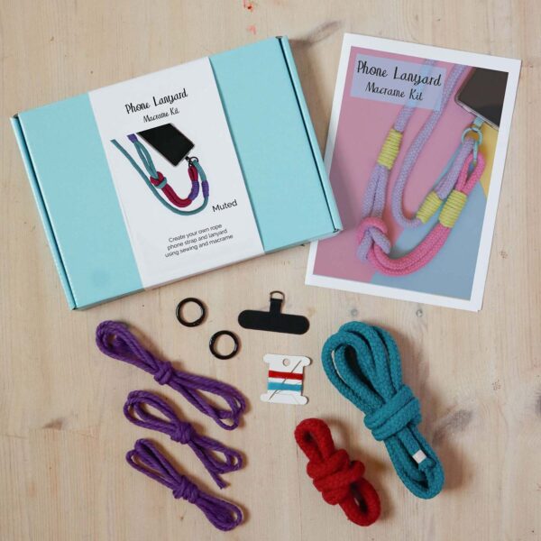 Macrame lanyard kit contents in muted . A rope lanyard in teal blue, crimson and purple with black fixings and phone tether tab